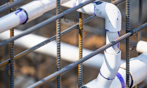 Newly Installed PVC Plumbing Pipes and Steel Rebar Configuration At Construction Site